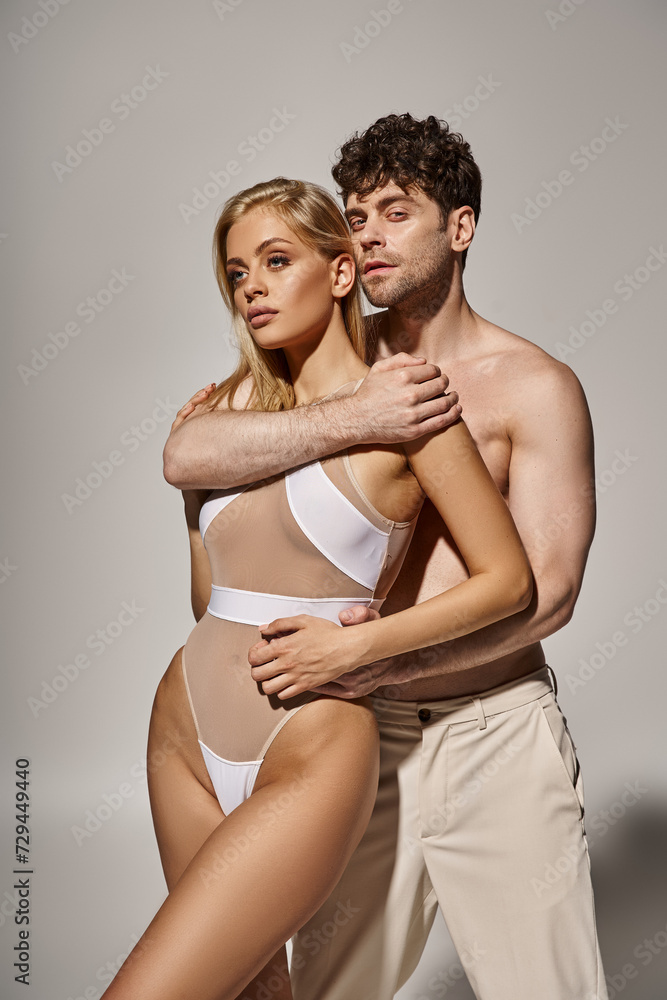 shirtless man with muscular body embracing pretty young woman on grey background, sexy couple shirtless man with muscular body embracing pretty young woman on grey background, sexy couple