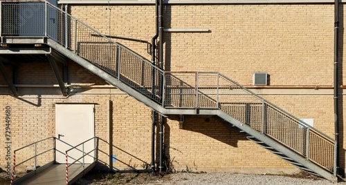 Emergency exit staircase and emergency door on a brick wall facade. Background for copy space.