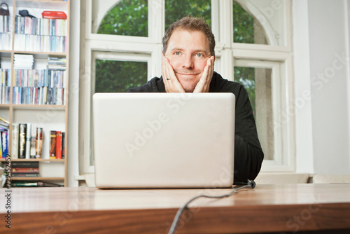 Man sitting content behind his laptop at a table. Munich, Germany photo
