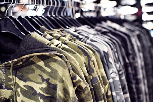 Outerwear, row of military-colored hoodies on hangers in a clothing store close-up, soft selective focus.