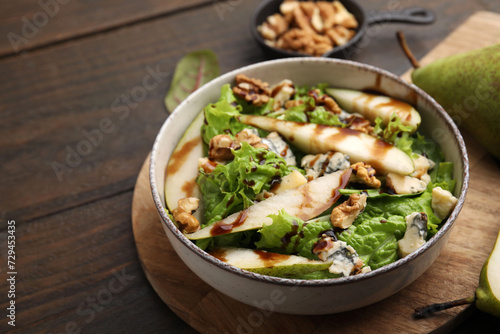 Delicious pear salad with sauce in bowl on wooden table, closeup. Space for text