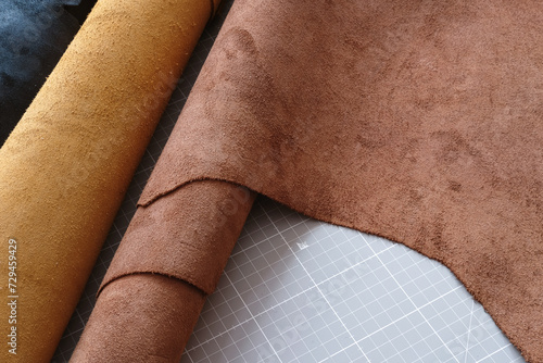 Brown leather hides from italian tannery, calfskin and cowhide rolled on table