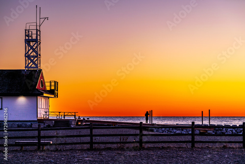 Photography Optomisim: as the sun rises over water a woman in silhouette stands on a dock lo
