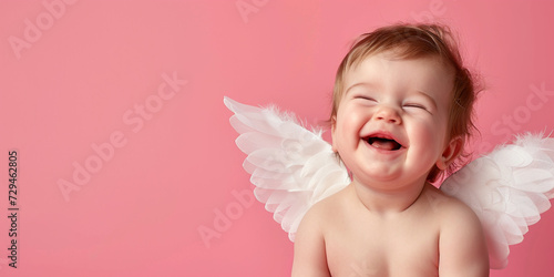 A Baby With Angel Wings Is Smiling On A Pink Background photo