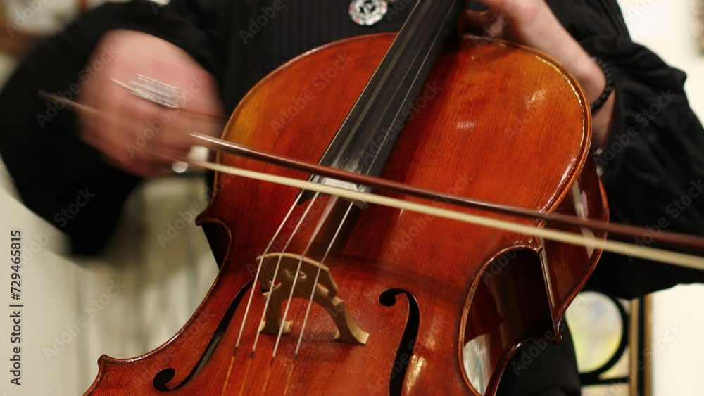 A man in a black shirt plays the cello. A man in a black shirt plays the cello.
