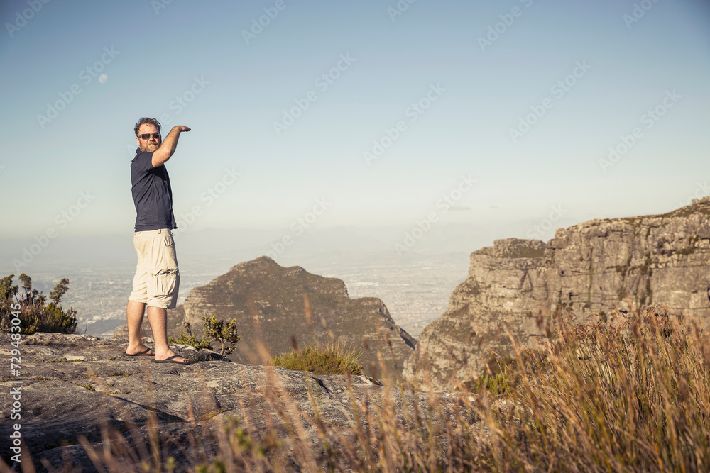 Man standing on a cliff looking at the camera and off into the distance on Table Mountain. Cape Town, South Africa Man standing on a cliff looking at the camera and off into the distance on Table Mountain. Cape Town, South Africa