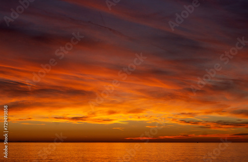 Sunset over the sea. Bright orange and red clouds. Dramatic sky