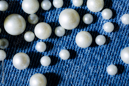 White pearls scattered on blue denim jeans texture background fashion design © Didot Studio