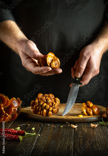 Chef preparing Flammulina velutipes mushrooms. Knife and mushrooms in the hands of a cook in the kitchen. photo