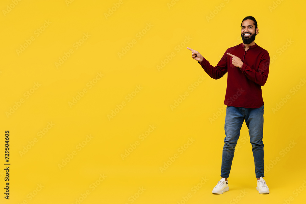 Cool positive young eastern guy pointing at blank space Cool positive young eastern guy pointing at blank space