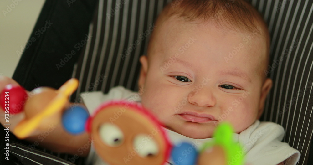 Obraz premium Baby newborn in chair seated with spinning toy in the foreground
