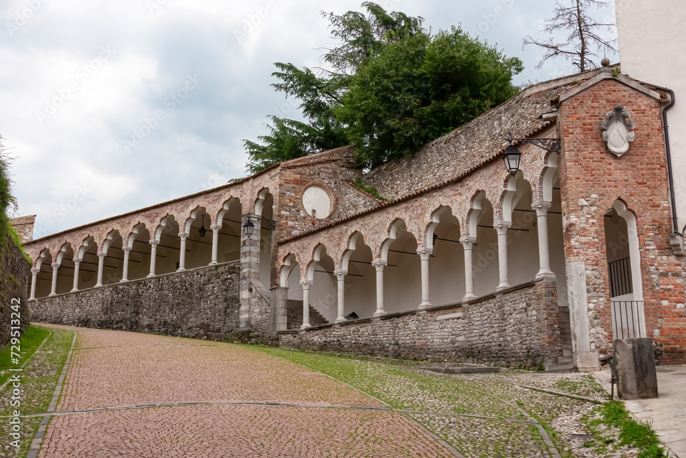 Scenic pedestrian path along renaissance Venetian gothic style arcade leading to castle of Udine, Friuli Venezia Giulia, Italy, Europe. Italian architecture columns and arches. Travel destination