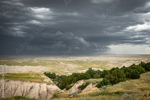 Dark storm clouds over the panoramic landscape of the Great Plains of South Dakota with a mule deer in the bottom of the frame.  