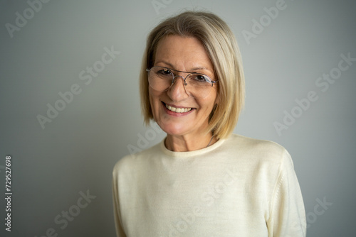 Image of happy senior business woman posing isolated over grey wall background. Copy space. Portrait of beautiful middle aged woman with blondie hair. photo