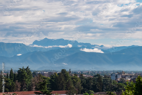 Aerial panoramic view of historic city of Udine, Friuli Venezia Giulia, Italy, Europe. Viewing platform form castle of Udine. Cloudy overcast day. Distant view of mountains of Alps, border to Austria