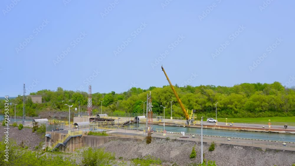 Establishing shot of canal and cargo ship with green forest background in Toronto, Canada, North America. Day time on May 2023. ProRes 422 HQ. Establishing shot of canal and cargo ship with green forest background in Toronto, Canada, North America. Day time on May 2023. ProRes 422 HQ.