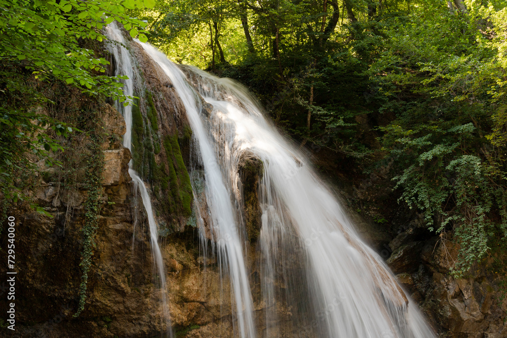 Fototapeta premium A beautiful landscape of a small deep waterfall with flowing water on the European mountain river.