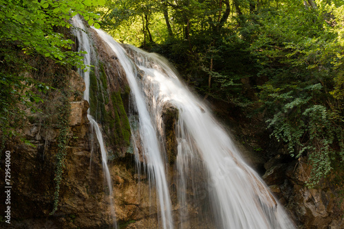 A beautiful landscape of a small deep waterfall with flowing water on the European mountain river.