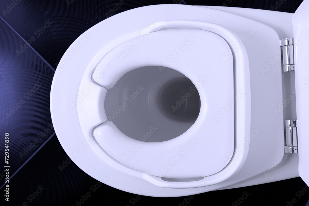 Close-up of a white color baby toilet seat, on a white toilet bowl in a toilet with a black tiled floor. Close-up of a white color baby toilet seat, on a white toilet bowl in a toilet with a black tiled floor.