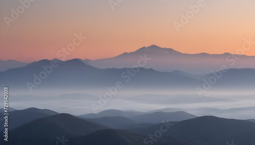 Sunrise Over a Range of Misty Mountains with a Gradient Sky © Lucas