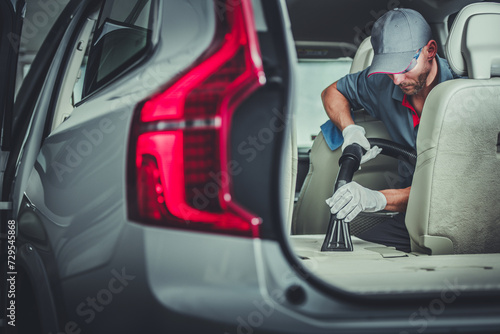 Car Dealership Worker Vacuuming and Cleaning a Vehicle