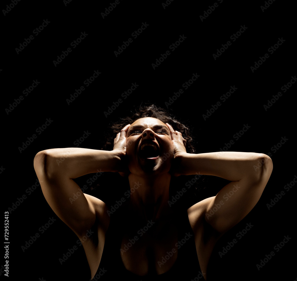 Portrait of a screaming woman in the shadow, hold her head , closed eyes on a black background Portrait of a screaming woman in the shadow, hold her head , closed eyes on a black background