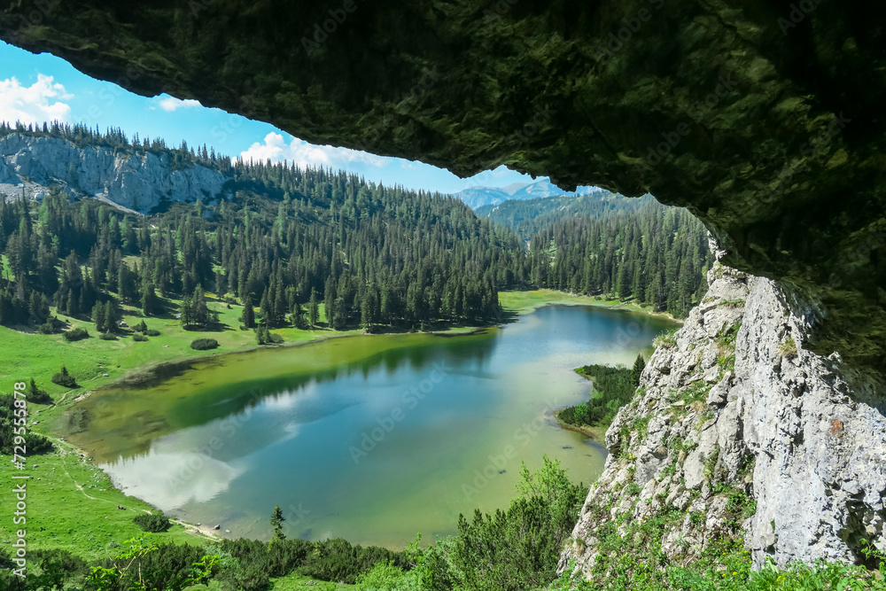 Idyllic cave Drachenhoehle with panoramic view of alpine lake Sackwiesensee in Hochschwab mountains, Styria, Austria. Wanderlust in wilderness of Austrian Alps, Europe. Natural arch rock formation