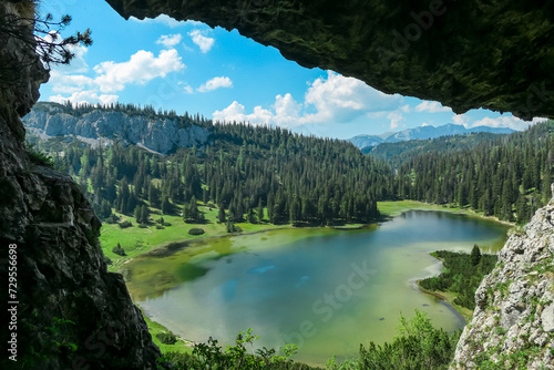 Idyllic cave Drachenhoehle with panoramic view of alpine lake Sackwiesensee in Hochschwab mountains, Styria, Austria. Wanderlust in wilderness of Austrian Alps, Europe. Natural arch rock formation