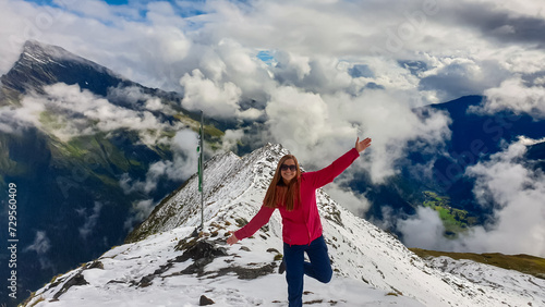 Woman on top of majestic mountain peak Arnoldhoehe in Ankogel Group, High Tauern National Park, Austria. Wanderlust in untamed Austrian Alps, Europe. Cloud covered terrain in idyllic hiking atmosphere photo