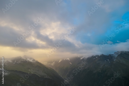 Panoramic view from mountain peak Arnoldhoehe in Ankogel Group, High Tauern National Park, Austria. Wanderlust in untamed snow covered Austrian Alps. Cloud covered terrain in idyllic hiking atmosphere