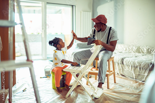 Father and daughter having fun while renovating at home photo