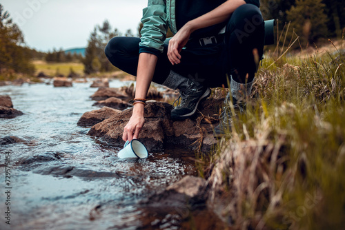 Hiker filling water bottle from a mountain stream photo