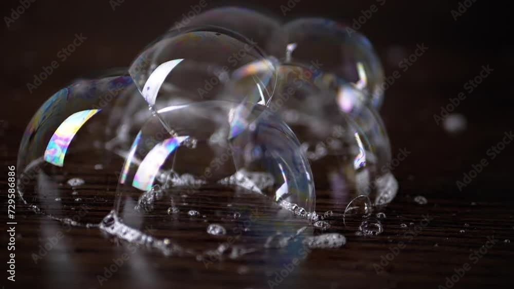 Close up, Lots of Colorful Stuck Together Soap Bubbles on a Wooden Surface. Structure of connected transparent large rainbow bubbles. Bubble bunch. Soap foam. Blurred brown background. Abstract. Close up, Lots of Colorful Stuck Together Soap Bubbles on a Wooden Surface. Structure of connected transparent large rainbow bubbles. Bubble bunch. Soap foam. Blurred brown background. Abstract.