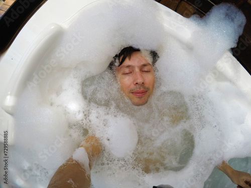 homem relaxando em banheira jacuzzi de espuma sais  photo