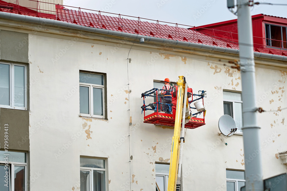 Building Getting Repaired Workers repairing wall facade, painting and plastering old building ...