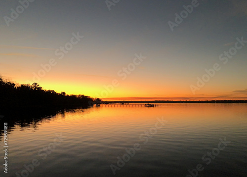 Sun setting behind trees along the shoreline of the St. Johns River in Florida