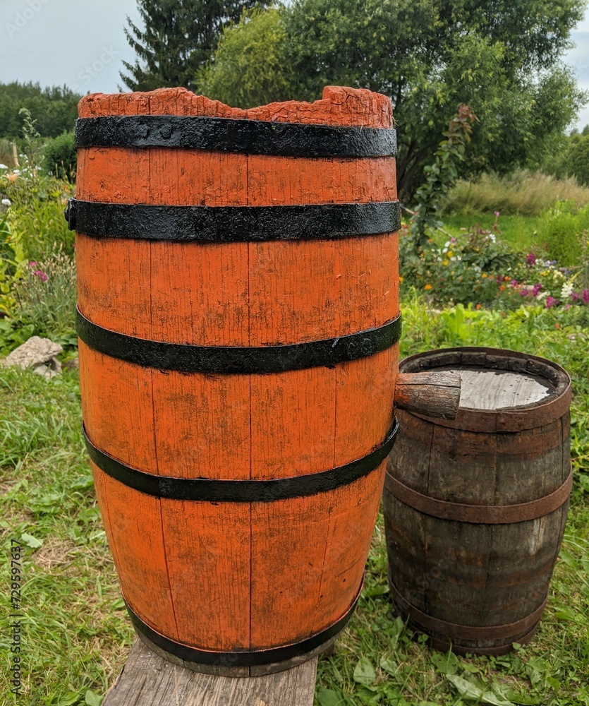 orange old wooden barrel in the rural summer garden. orange old wooden barrel in the rural summer garden.
