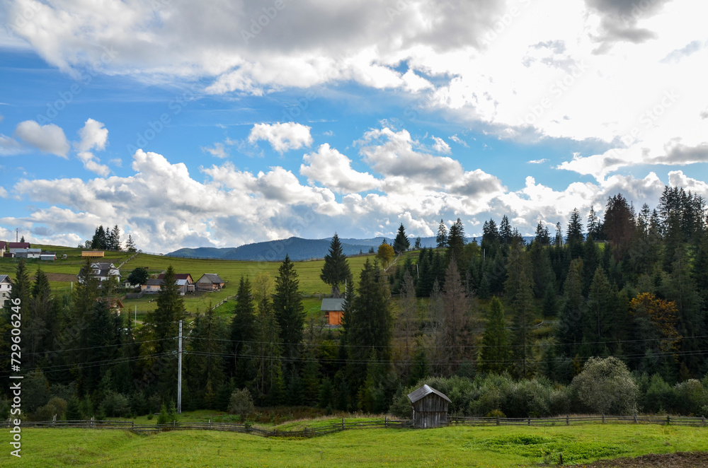 Picturesque landscape with a view of the mountain landscape, green meadows and forest. Rural houses located on the slopes of the mountains. Carpathians, Ukraine 