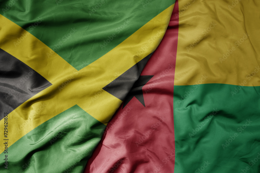 Obraz premium big waving national colorful flag of guinea bissau and national flag of jamaica .