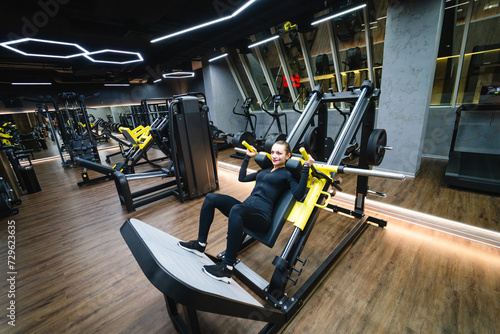 Young woman doing exercises on bench press in the gym