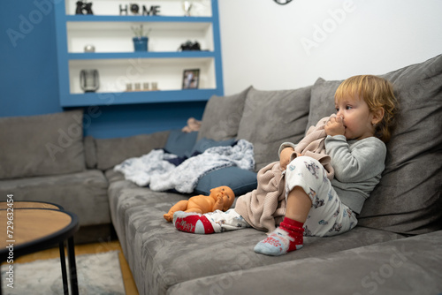 Little baby girl laying on a couch with her blanket, ready to sleep