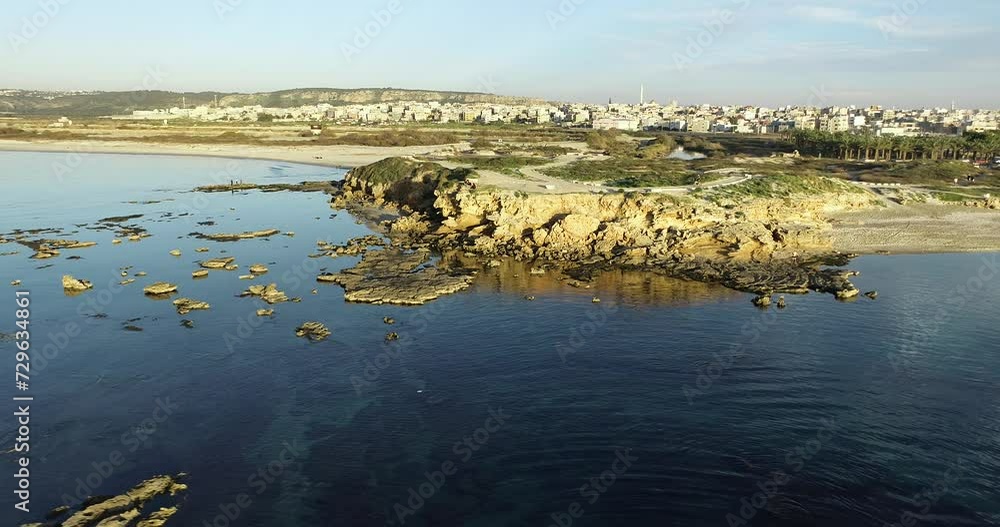 Aerial footage of the amazing beach of Jisr az-Zarqa with fishermen fishing in the water, in front of a stunning sunset.