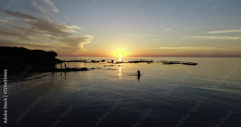 Aerial footage of the amazing beach of Jisr az-Zarqa with fishermen fishing in the water, in front of a stunning sunset.
