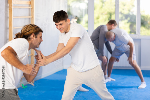 Guy and man are training in gym practicing palm grab technique