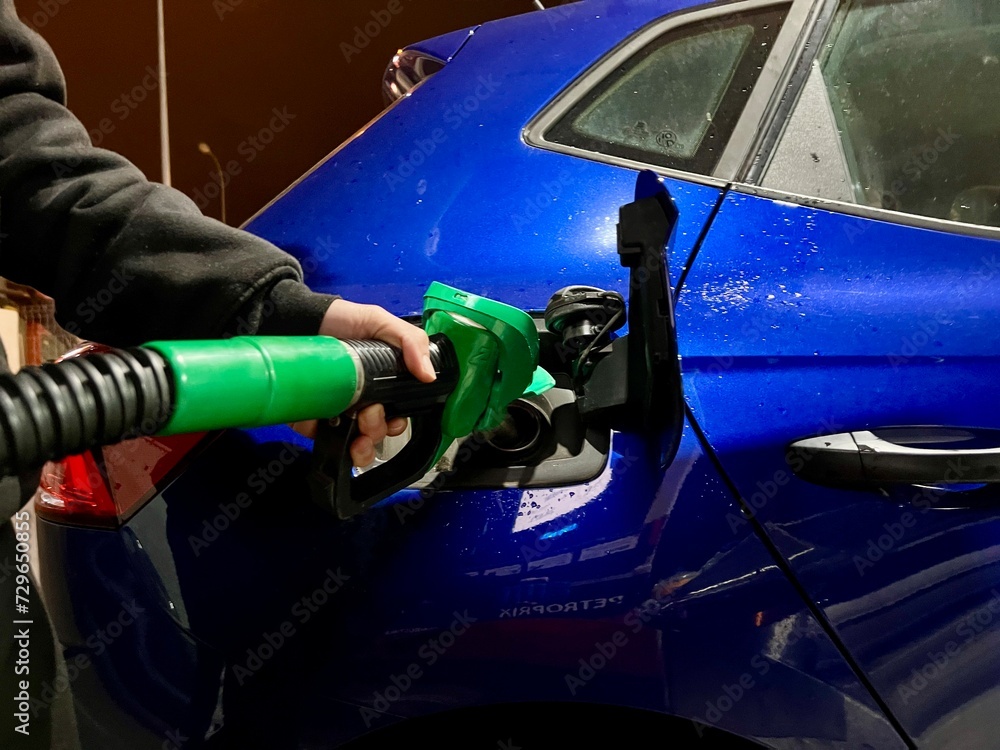 Refueling a Vibrant Blue Car at a Gas Station on a Rainy Day