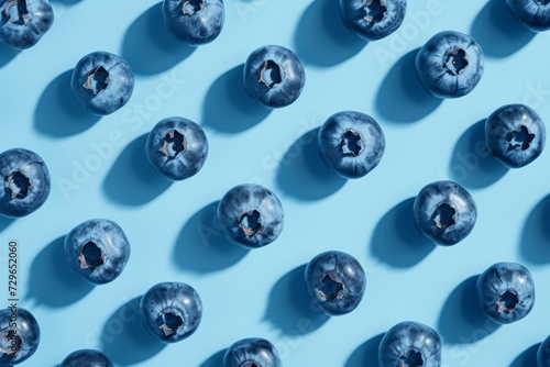 A vibrant display of nature's sweetness as a cluster of ripe blueberries rests upon a serene blue canvas, beckoning with their luscious hue and irresistible taste