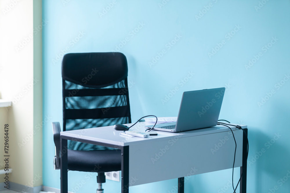 Empty workplace in the office: laptop, table and armchair.