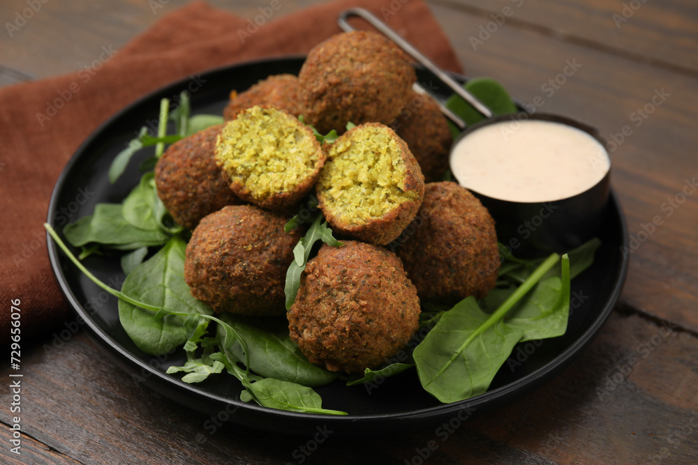Delicious falafel balls, herbs and sauce on wooden table Delicious falafel balls, herbs and sauce on wooden table