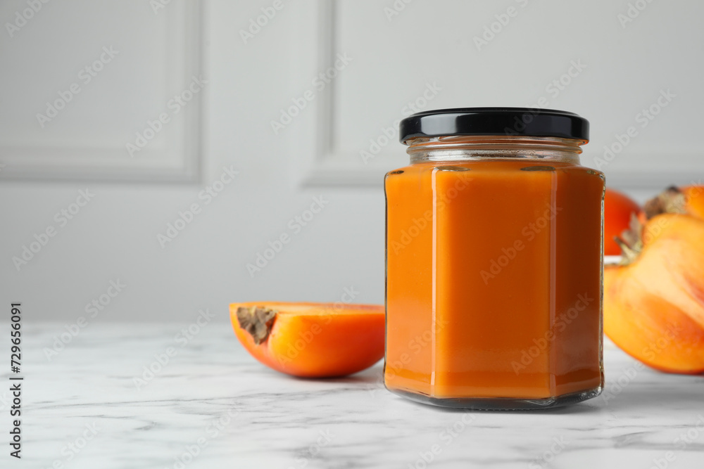 Delicious persimmon jam and fresh fruits on white marble table. Space for text Delicious persimmon jam and fresh fruits on white marble table. Space for text