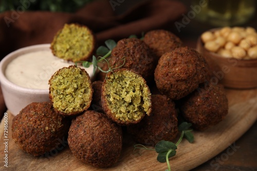 Delicious falafel balls and sauce on table, closeup